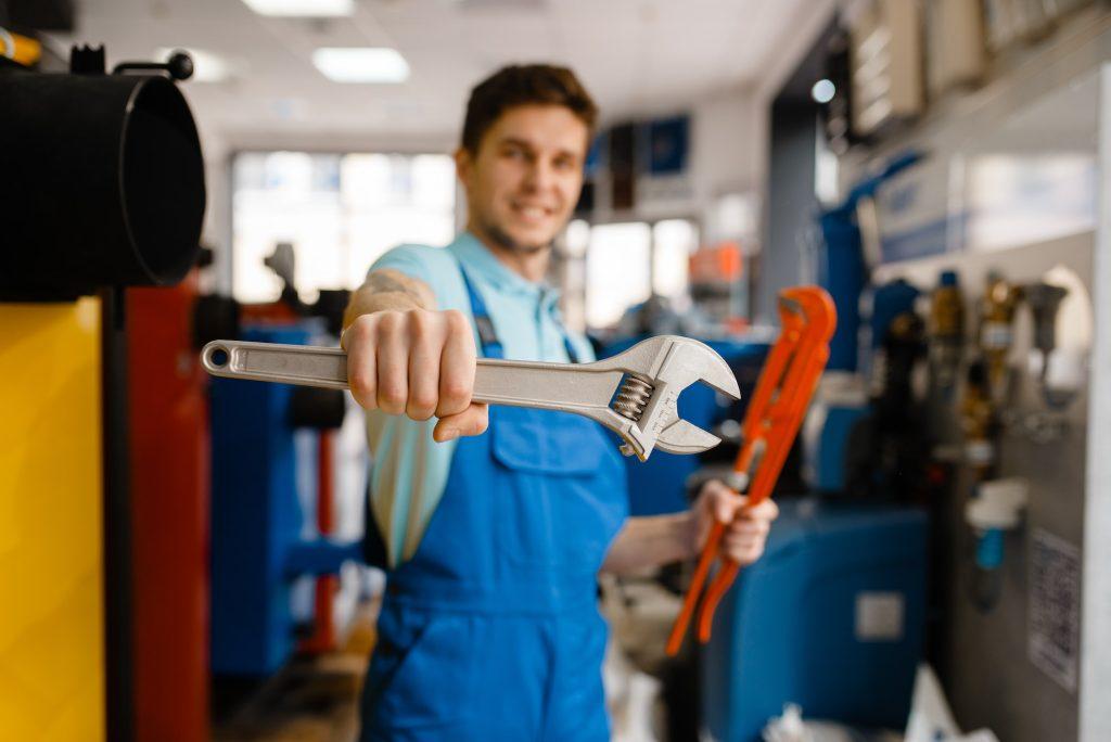 Plumber shows pipe wrenches in plumbering store